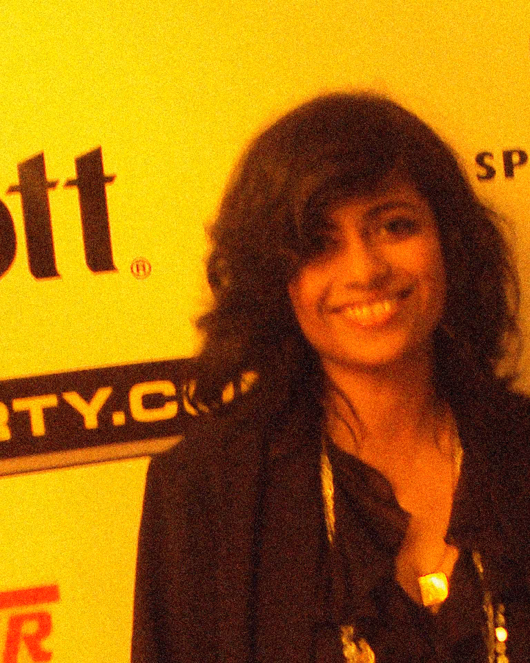 How to fix grainy photos: before noise reduction, a smiling full-face portrait with speckles in the hair and dark jacket